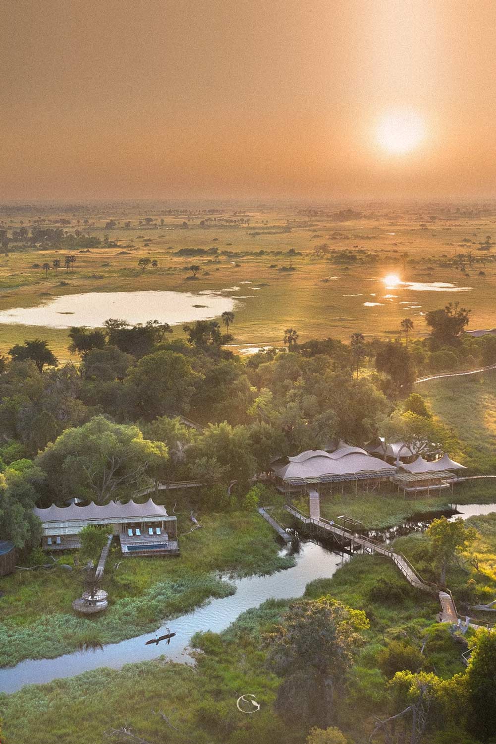 A lodge among the channels of the Okavango Delta at sunrise, seen from the air